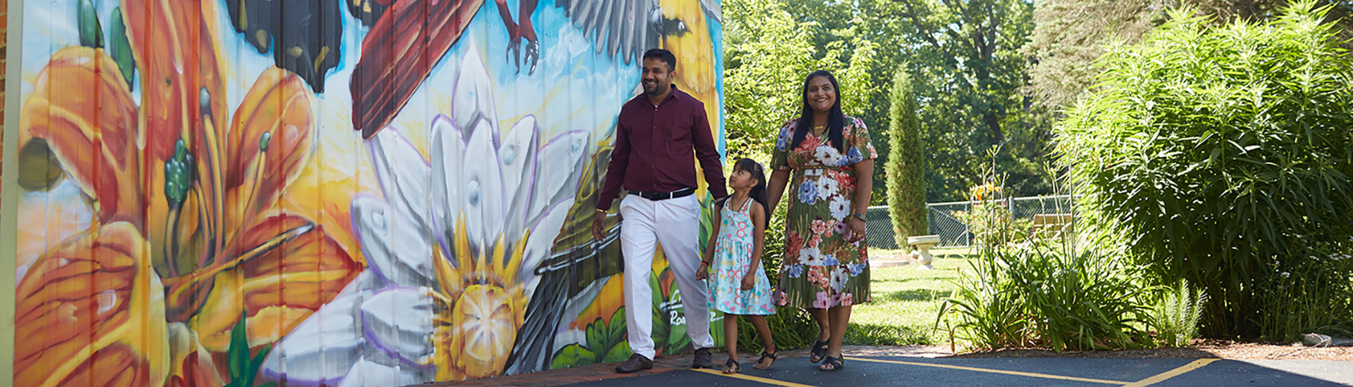 Family walking next to a mural wall with artwork on it.